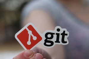 Une main avec un sticker du logo Git
