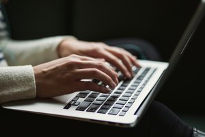 Mains posées sur le clavier d'un ordinateur portable.