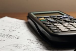 Une feuille avec des calculs et une calculatrice posées sur un bureau