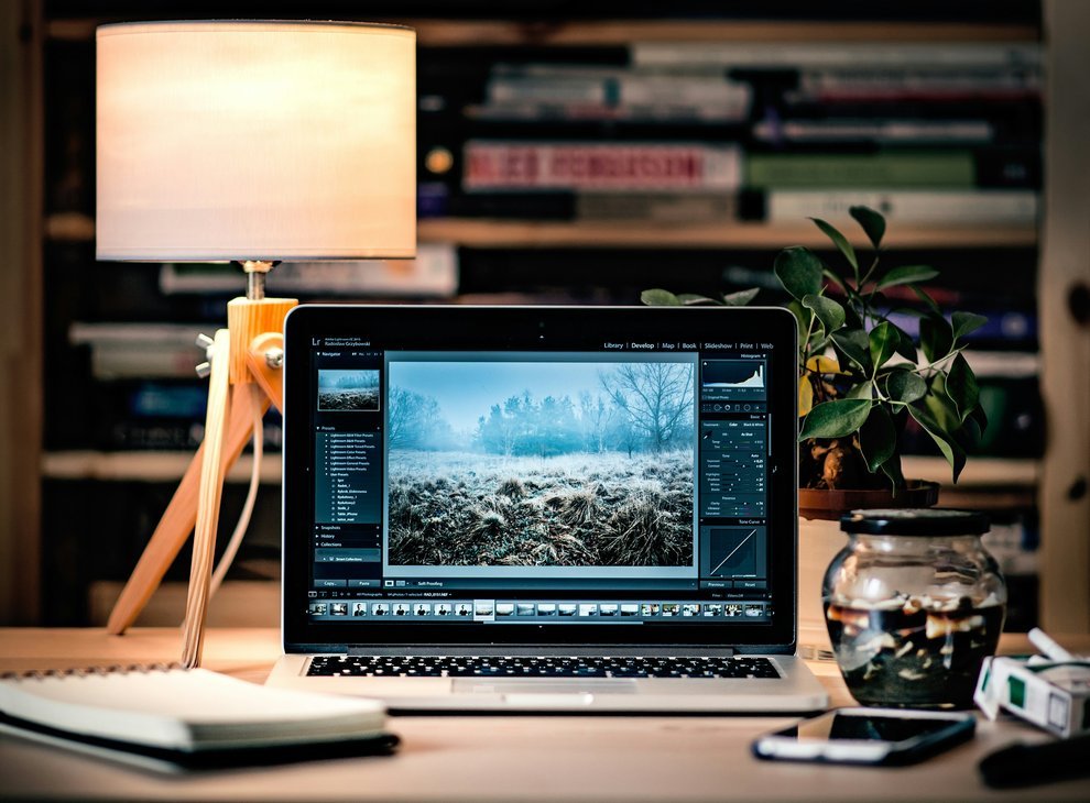 Un ordinateur portable posé sur un bureau, éclairé par une lampe, créant une ambiance de travail agréable