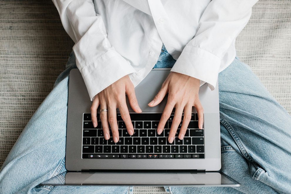 Les mains d'une femme tapant sur le clavier d'un ordinateur portable.